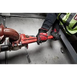 Person wearing Impact Cut Level 5 Goatskin Leather Gloves is tightening a red pipe wrench onto a valve in an industrial setting.