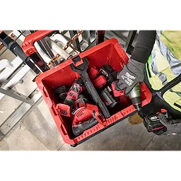 Divider for PACKOUT XL Crate inside a red storage box with various power tools and accessories, held by a person wearing gloves.