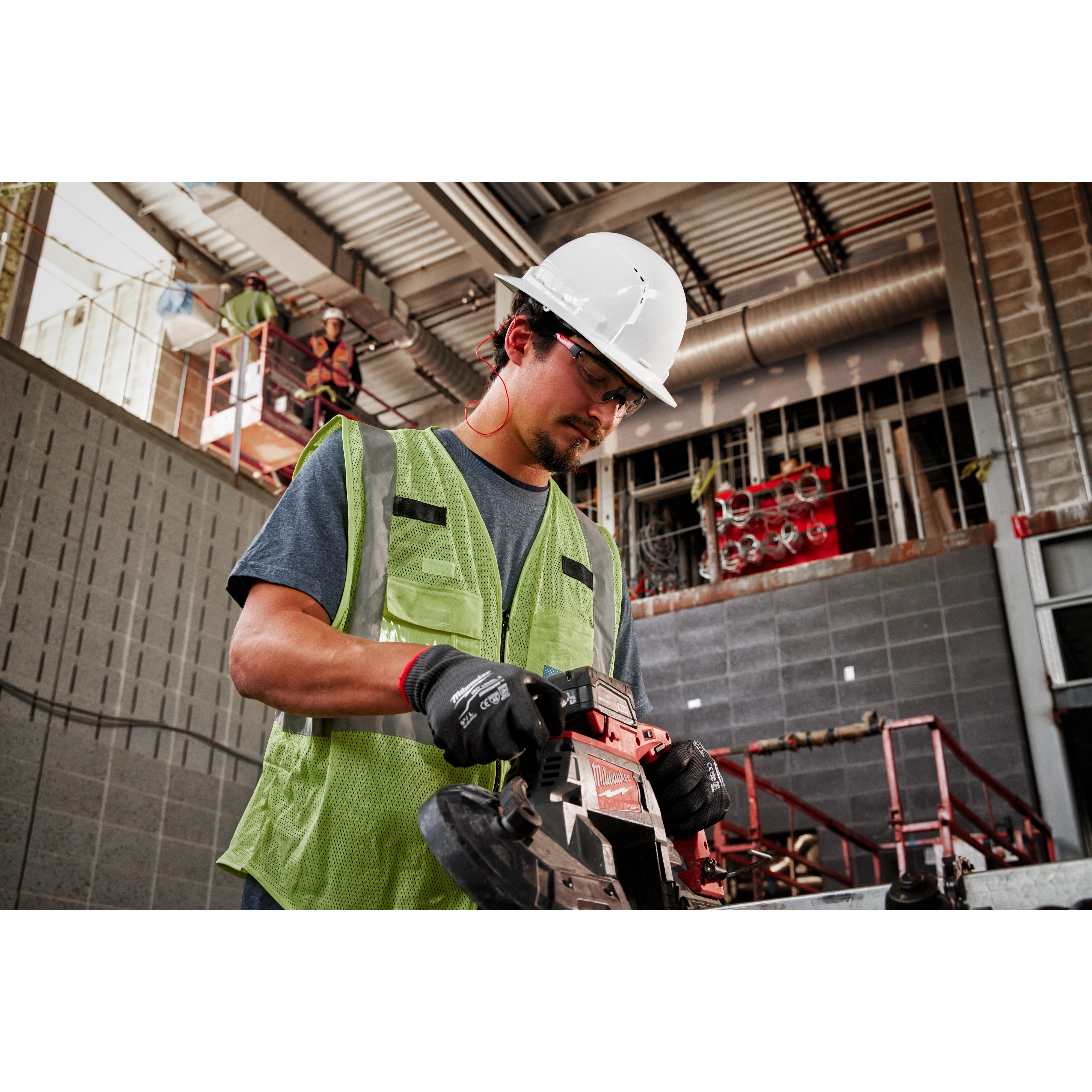 A construction worker operates a power saw while wearing a green safety vest and BOLT White Full Brim Vented Hard Hat w/6pt Ratcheting Suspension.