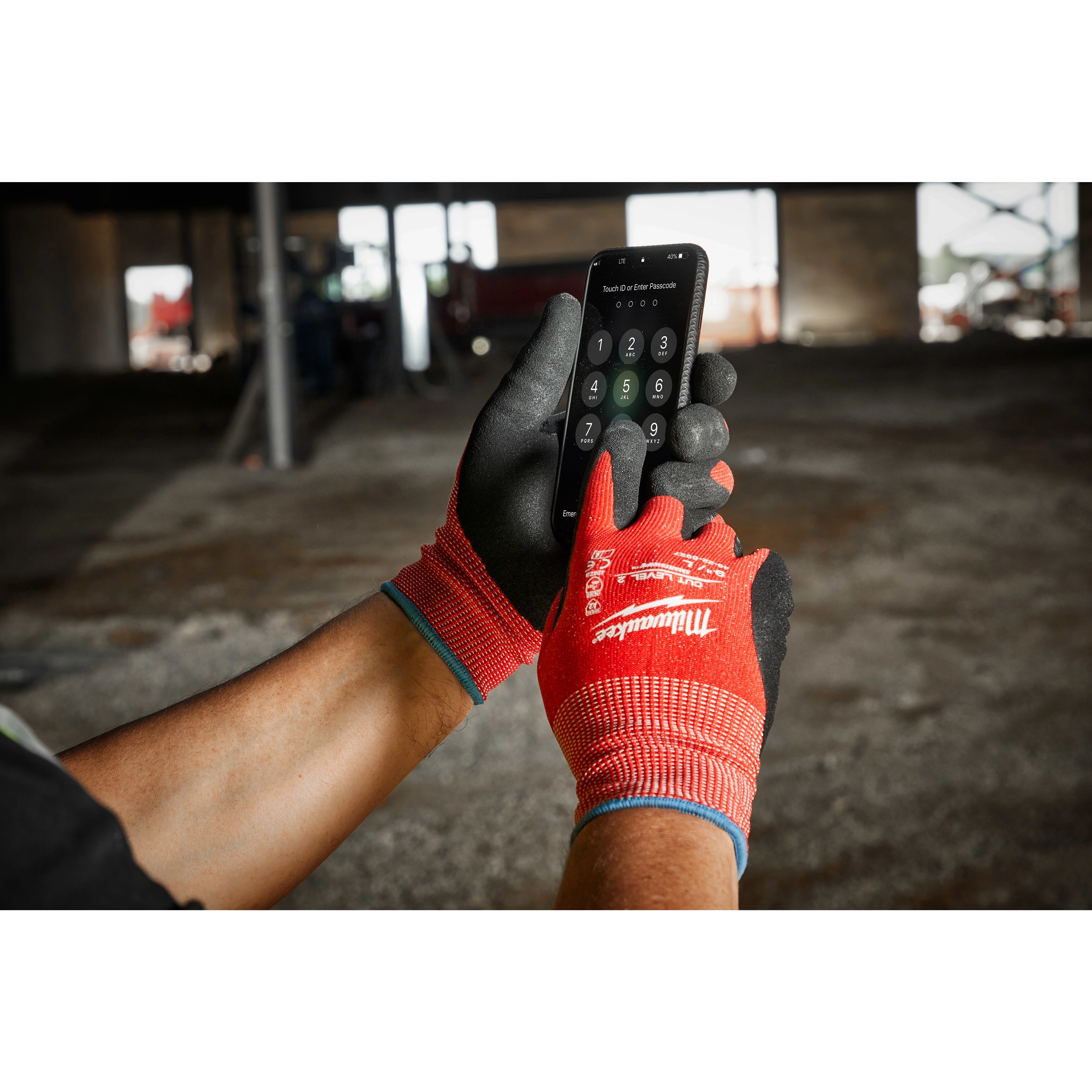 A person wearing Cut Level 2 Nitrile Dipped Gloves - L operates a smartphone in a construction area with a partially visible background.
