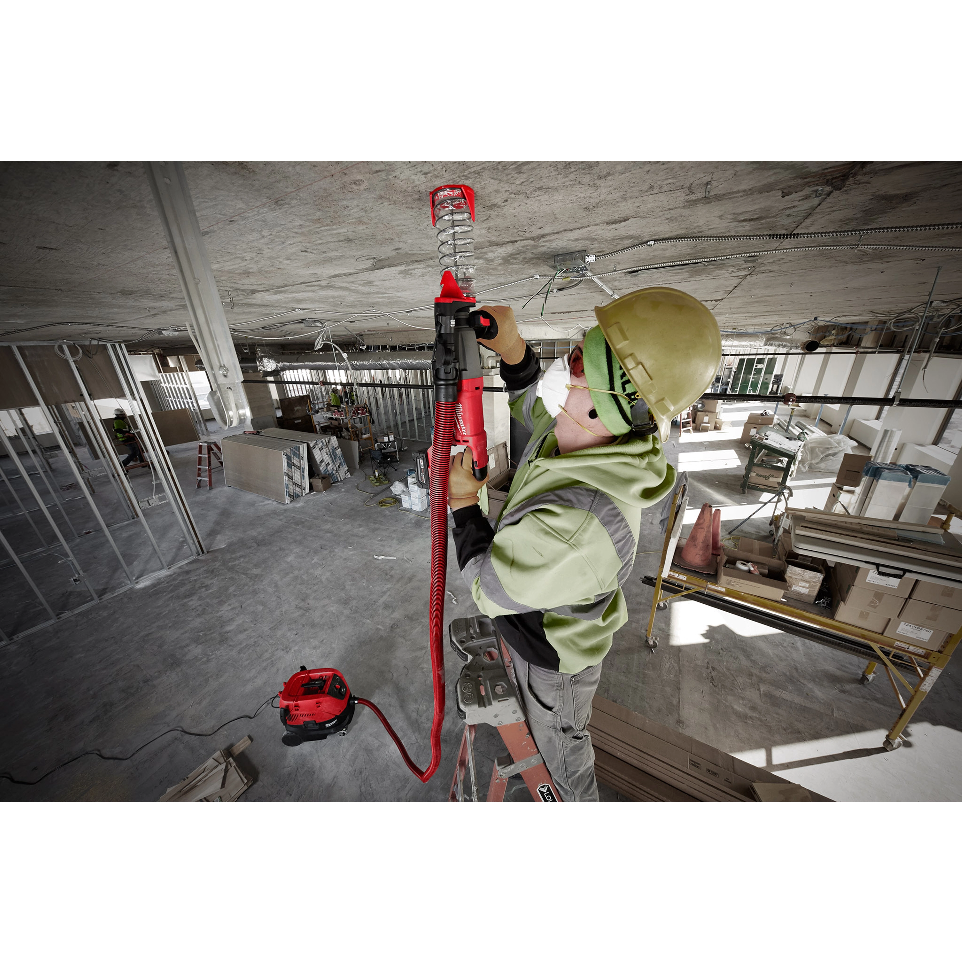 Worker on ladder using SDS+ DUST TRAP Drilling Shroud Bulk 10 to drill into a concrete ceiling on a construction site.