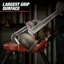 The Milwaukee adjustable pipe wrench is being used to grip a large metal pipe in a workshop. The text "LARGEST GRIP SURFACE" is displayed in the upper left corner.