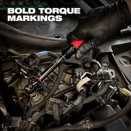 A gloved hand holds a 3/8” Drive Click Torque Wrench (50-250 in·lbf) amidst car engine components. Bold torque markings are visible.