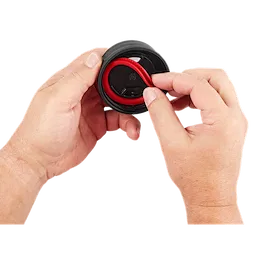 Hands holding the PACKOUT Sip Lid, featuring a black cap with a red, flexible spout being manipulated by the fingers.