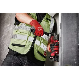 Person using a power tool wears red Cut Level 4 Nitrile Dipped Glove - L, with high-visibility green safety vest, working on a metal surface.