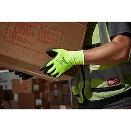 Person wearing a High Visibility Cut Level 1 Polyurethane Dipped Glove - L while handling a cardboard box in a warehouse.