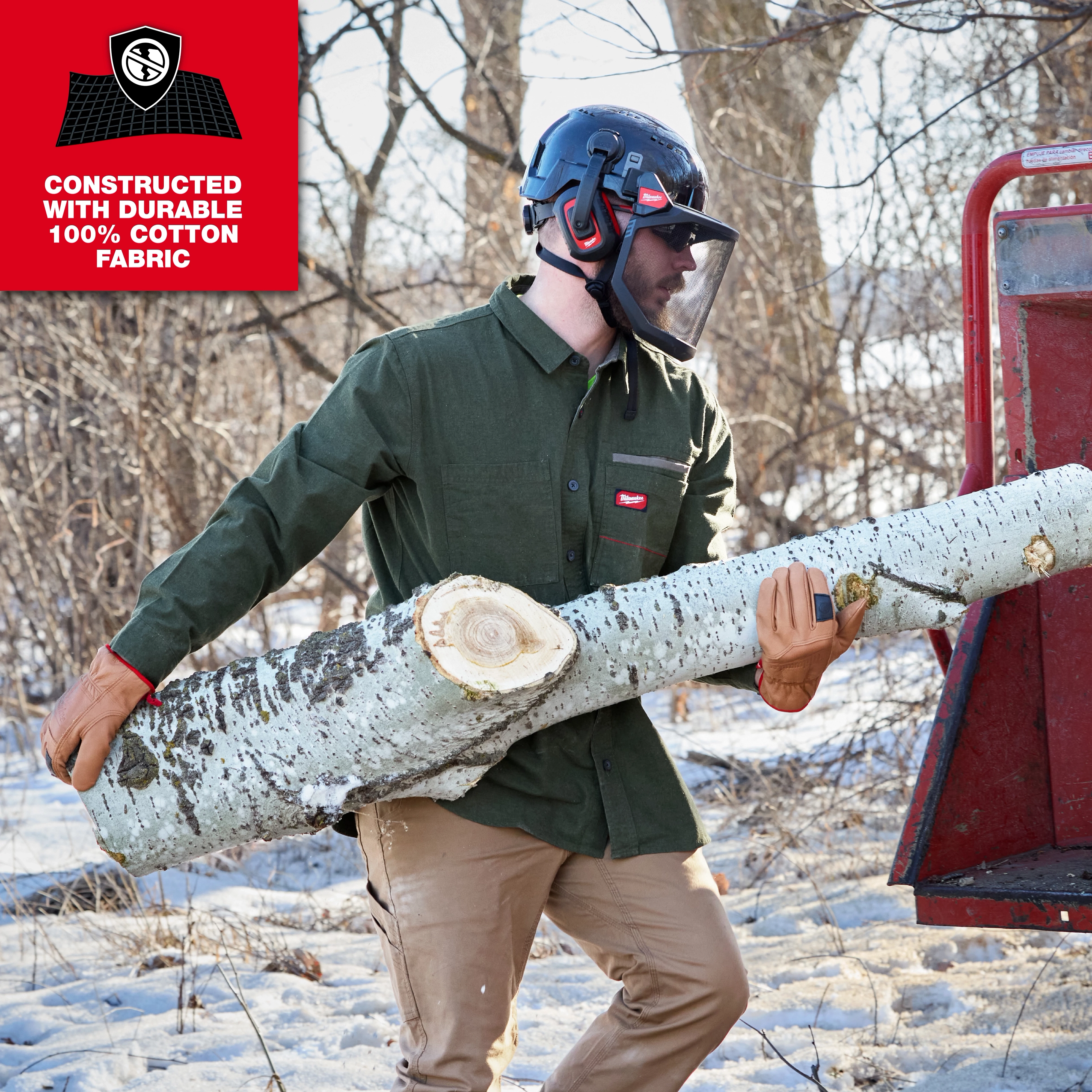 Person carrying a large log outdoors while wearing a GRIDIRON Flannel Shirt and safety helmet.