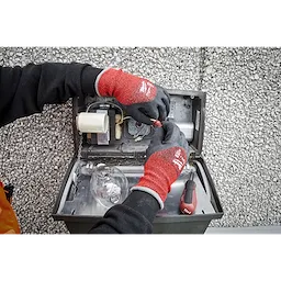 Person wearing Cut Level 4 Winter Dipped Gloves - L working on electrical components, with hands inside an open metal box.