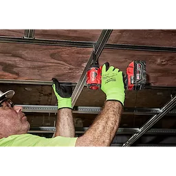 A person wearing bright green Hi Vis Cut Gloves is using a red cordless drill to secure a metal frame to a wooden ceiling.