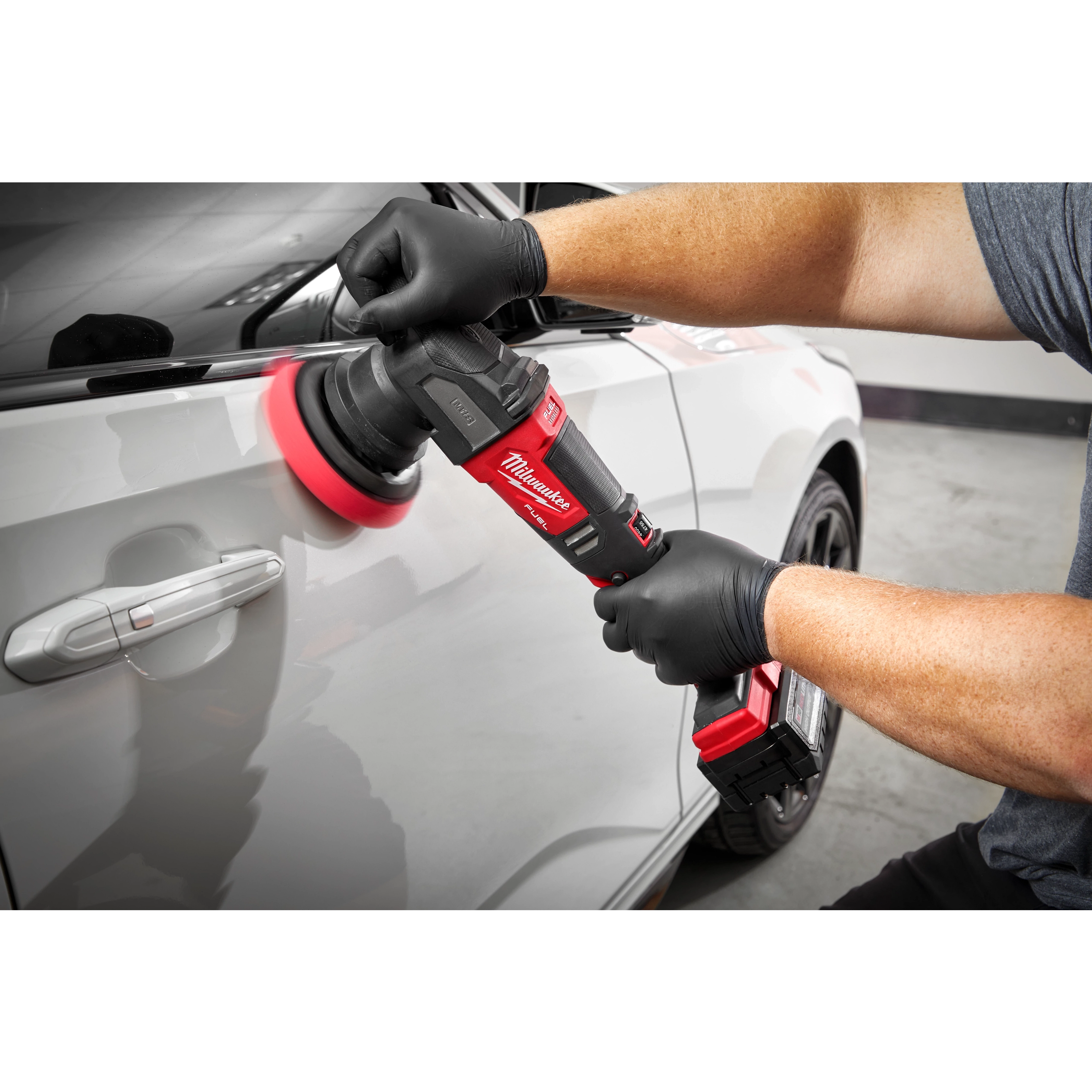 Man using the M18 FUEL 15 mm Random Orbital Polisher on the side of a car using the grip handle for easy use