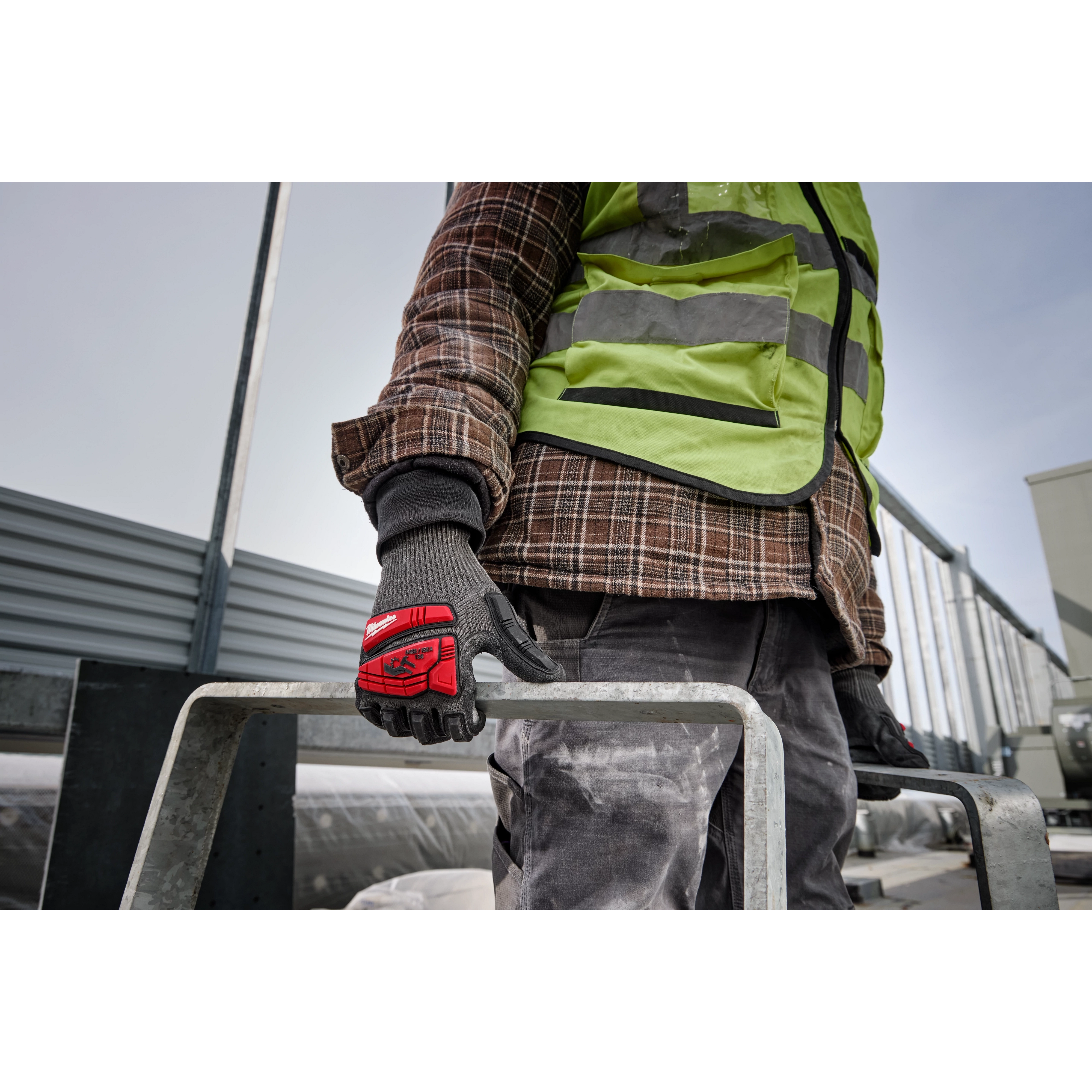 A person wearing an IMPACT CUT 5 NITRILE DIP GLOVE - L, holding a metal bar, dressed in work clothes and a high-visibility vest.