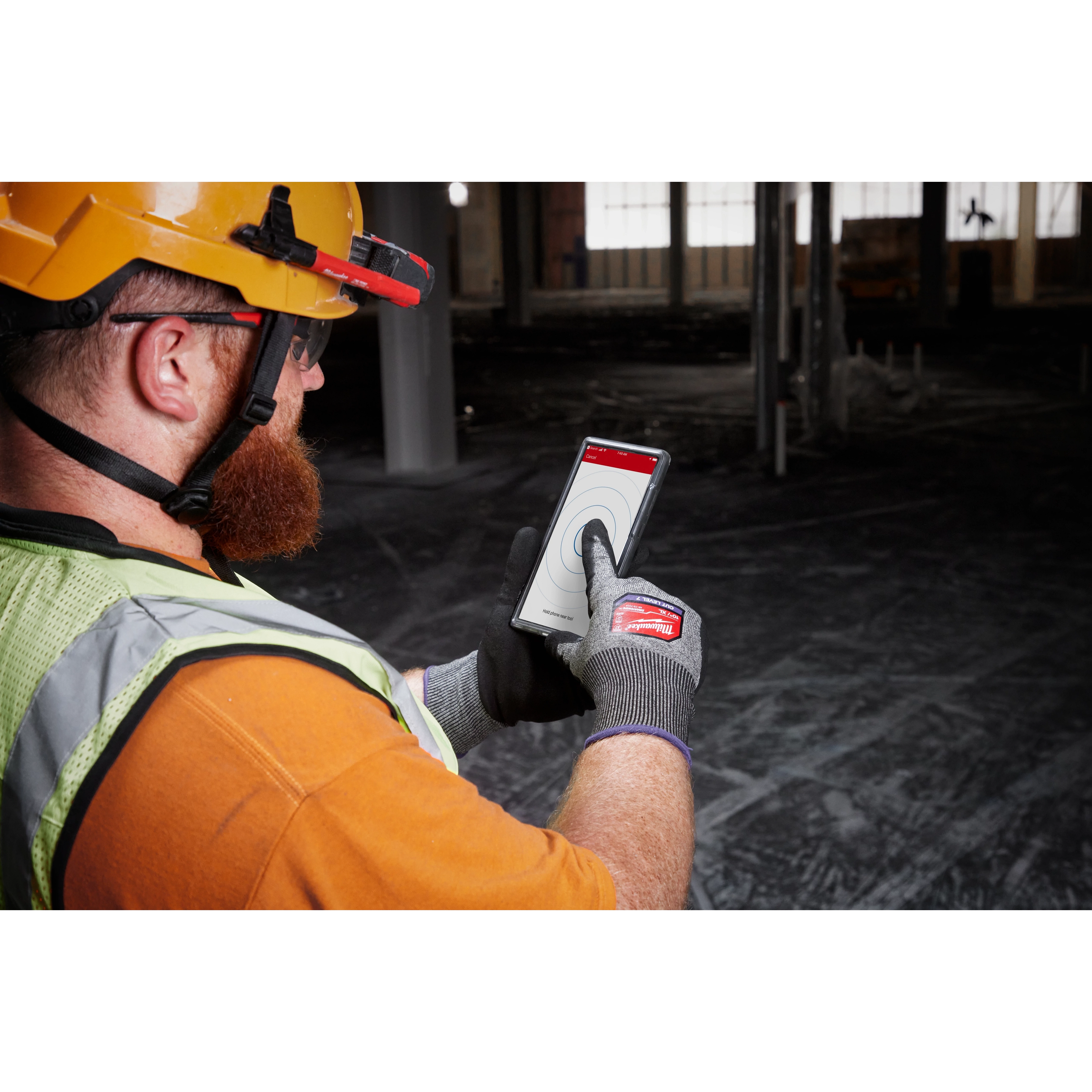 Man wearing a hard hat and safety vest using a touchscreen phone while wearing Cut Level 7 High-Dexterity Nitrile Dipped Gloves - L.