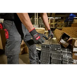 Worker wearing Cut Level 5 High Dexterity Nitrile Dipped Gloves w/ WEAR-DEFENSE Protection handling metal pieces.