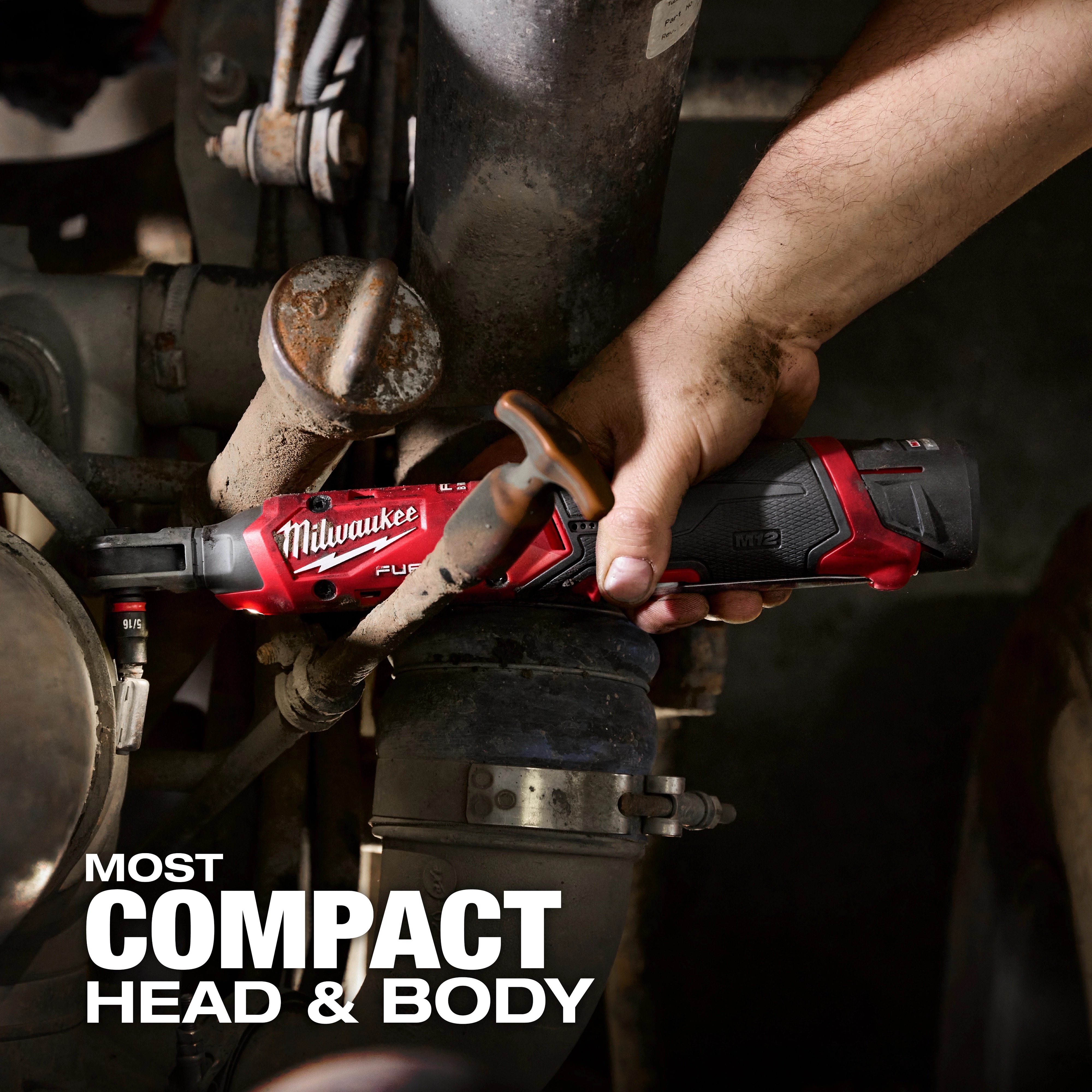 A person's hand uses the Milwaukee M12 FUEL™ 1/4" Ratchet to tighten a pipe fitting in a mechanical setup. The ratchet's compact head and body help in accessing tight spaces. Bold text reads "MOST COMPACT HEAD & BODY" in the image's bottom left corner.