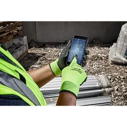 Worker wearing Hi Vis Cut Gloves uses a smartphone with blueprints on the screen at a construction site.