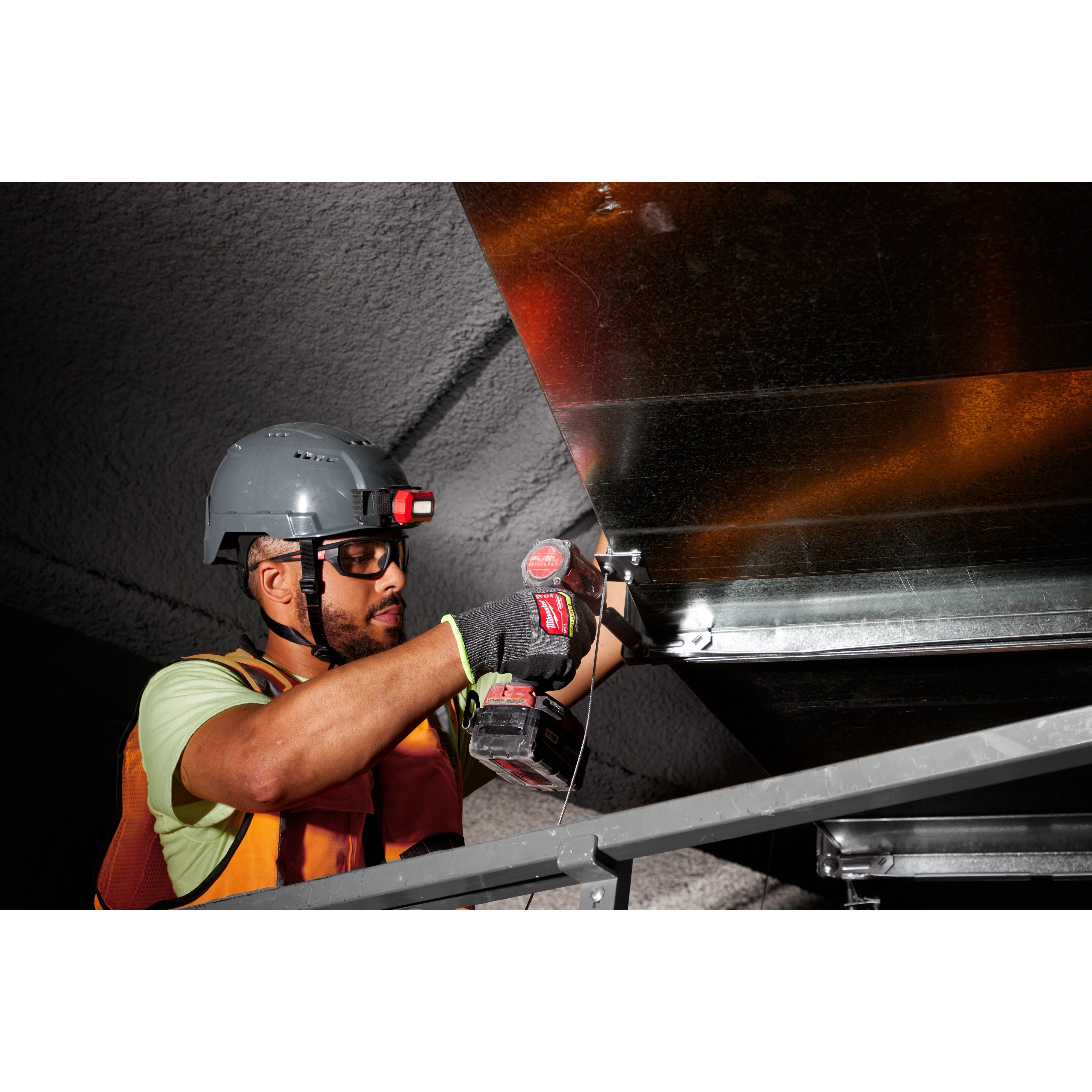 Worker wearing Cut Level 9 High-Dexterity Nitrile Dipped Gloves - L operates a power tool while installing sheet metal.