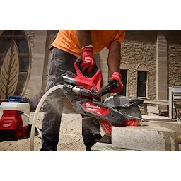 Worker cutting a concrete block with an M18 FUEL 9” Cut-Off Saw w/ ONE-KEY on a dusty construction site.
