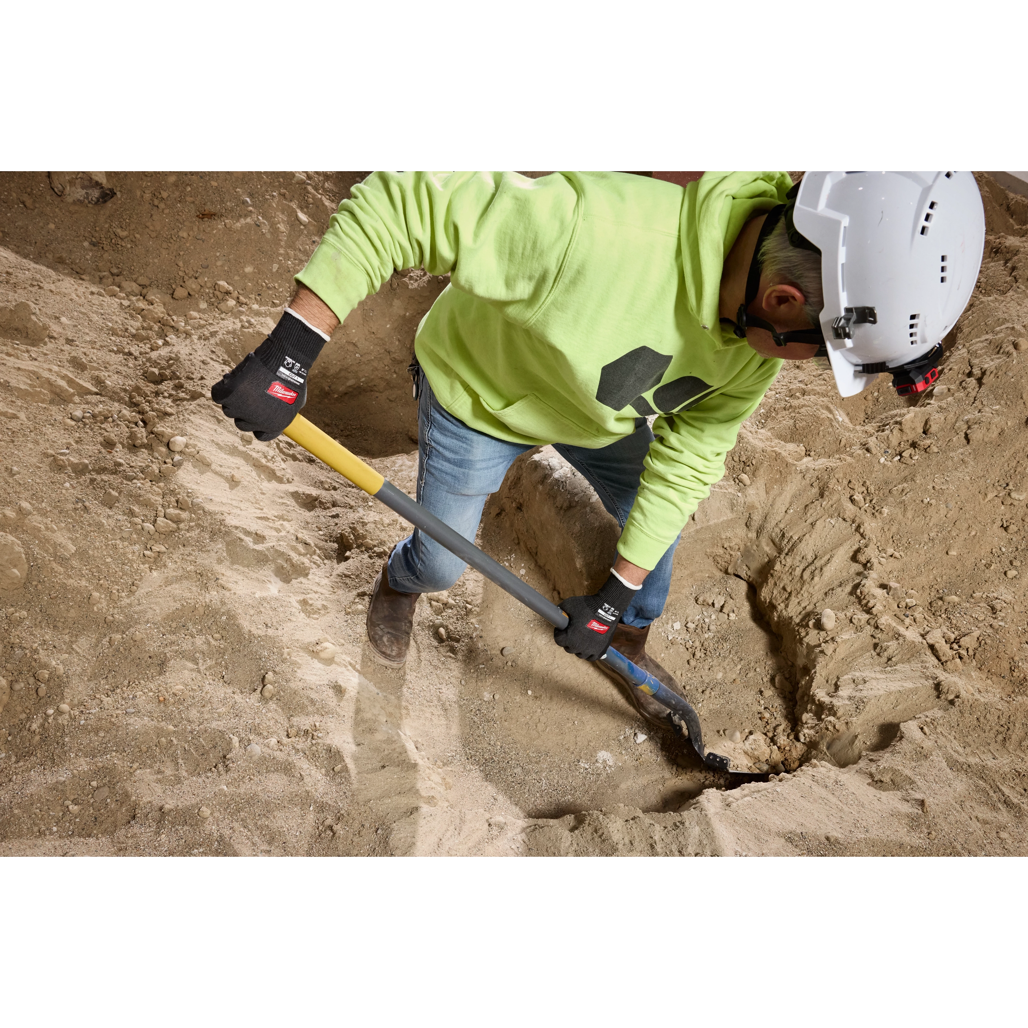 Worker digging in dirt with a shovel wearing Cut Level 1 Nitrile Dipped Gloves w/ WEAR-DEFENSE Protection.