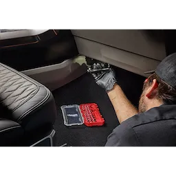 Mechanic using the 34pc 1/4” Drive Ratchet & Low-Profile Bit Socket Set inside a vehicle interior.