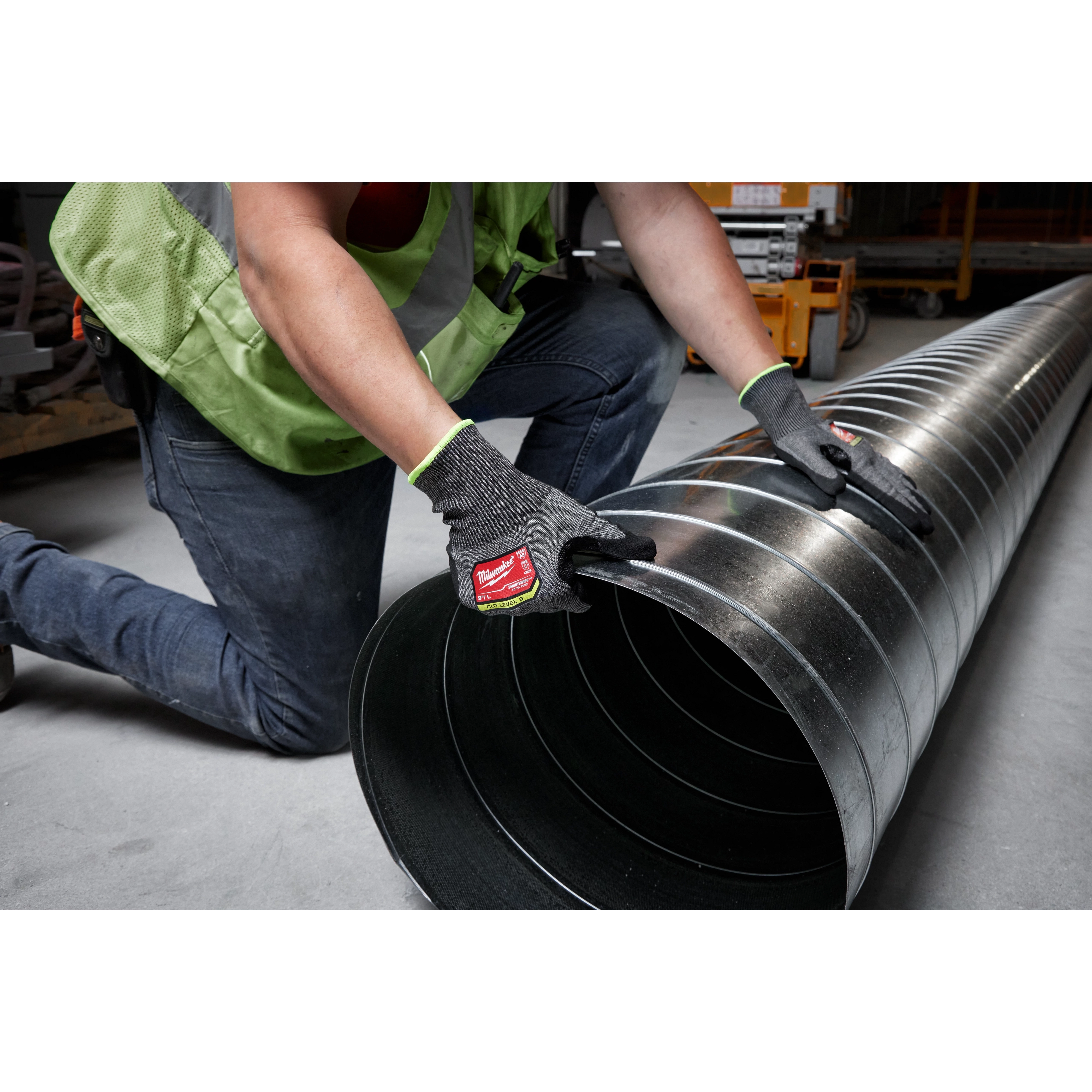 Person wearing Cut Level 9 High-Dexterity Nitrile Dipped Gloves - L, handling a large metal duct in a construction environment.