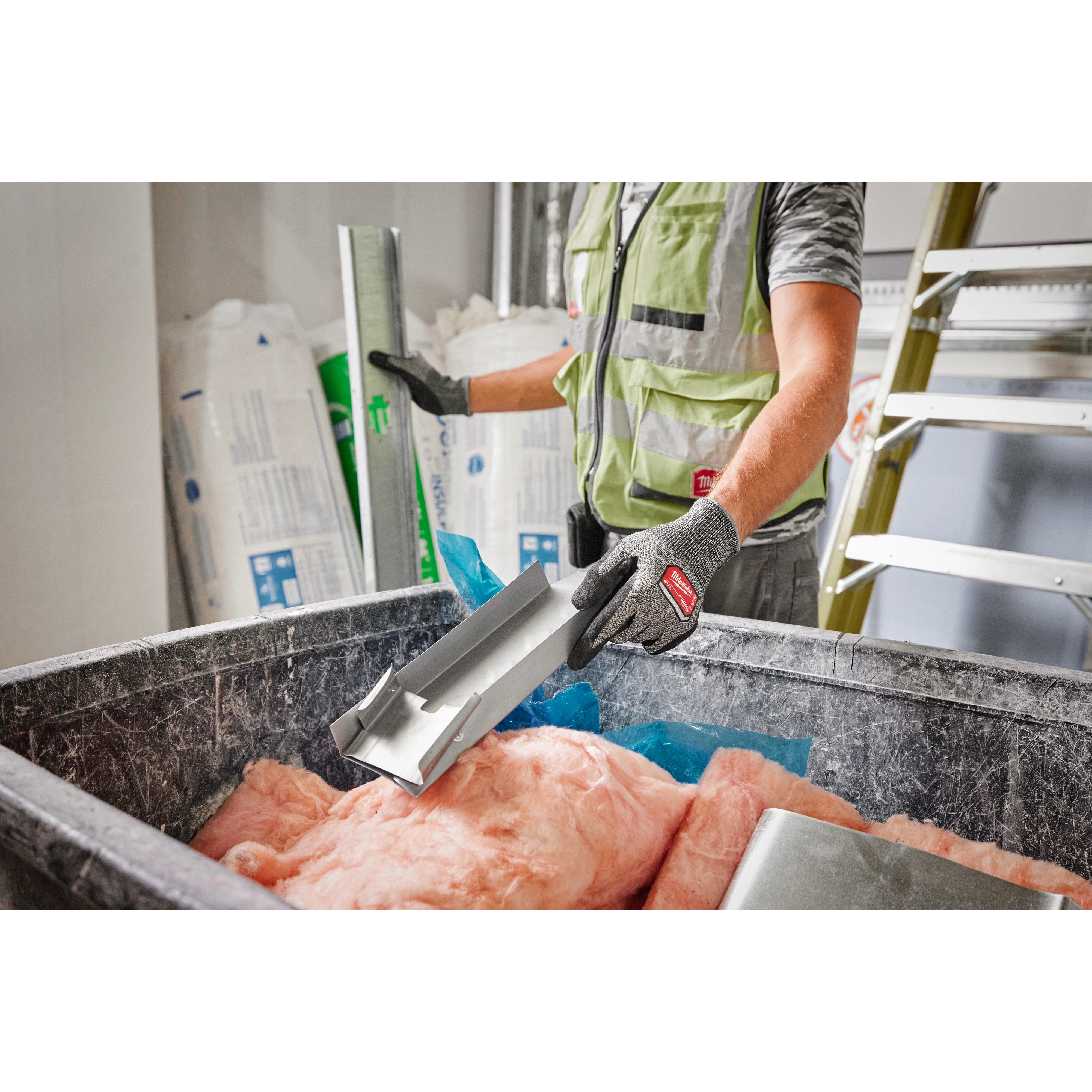 Person wearing Cut Level 4 High-Dexterity Nitrile Dipped Gloves - XL while handling construction materials in a workshop.