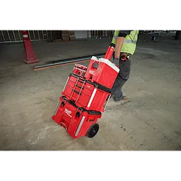 PACKOUT 18oz Insulated Bottle with Sip Lid is attached to a red tool storage system, being wheeled by a person on a worksite.