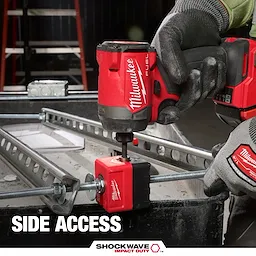 A Milwaukee drill is fastening a threaded rod nut using the SHOCKWAVE™ Impact Duty 3/8" Threaded Rod Nut Runner. A gloved hand holds the drill while the nut runner is attached to a metallic framework. The text on the image reads "Side Access." The equipment is in use at a construction site.