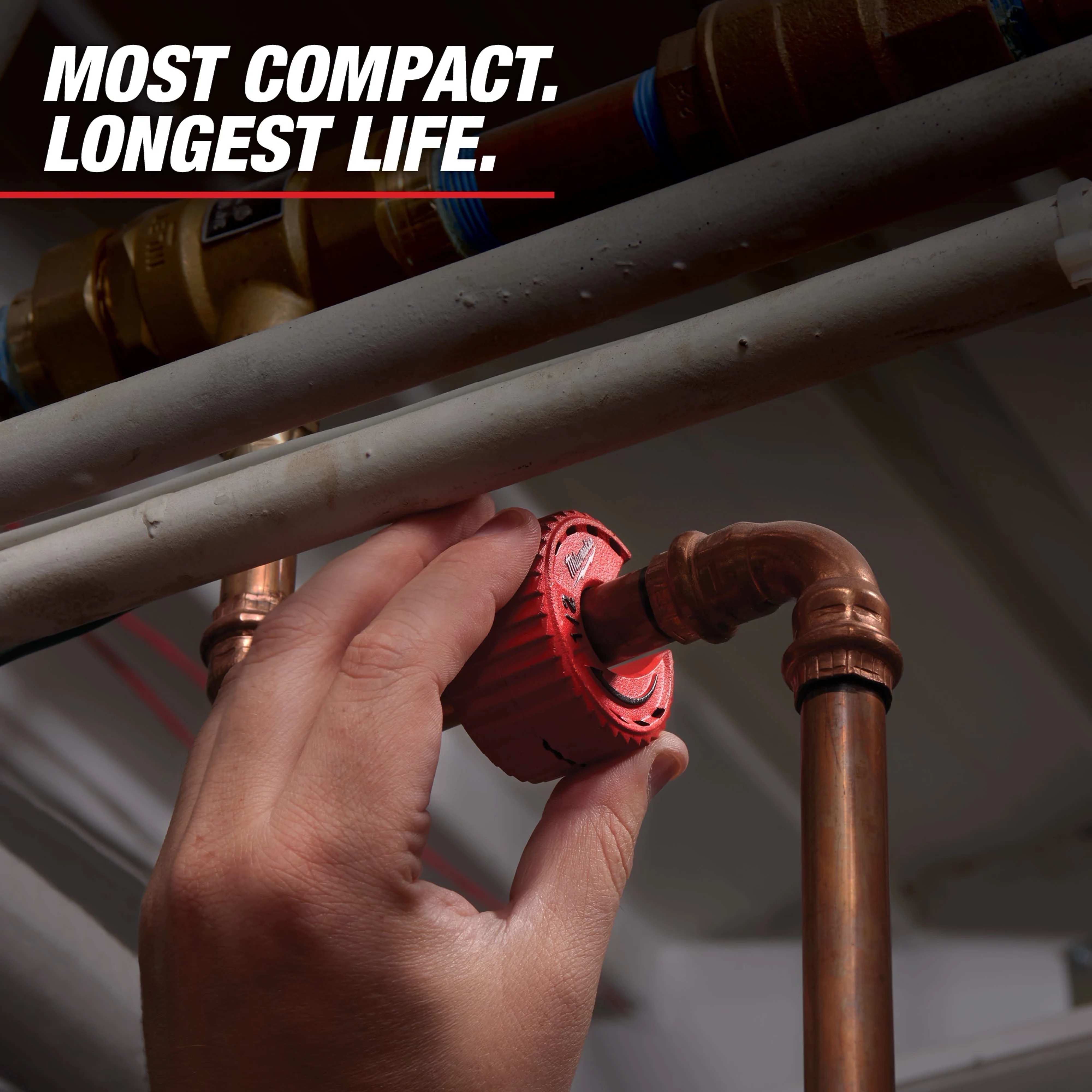 A hand is adjusting a red Liberty Pump check valve installed in a copper pipe system. The accompanying text reads "Most Compact. Longest Life." indicating the product’s features.