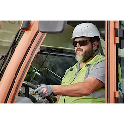 A construction worker wearing a white helmet, green safety vest, and gloves is operating machinery. The worker is also wearing Full Frame Safety Glasses with Removable Side Shields – Silver Mirrored Anti-Scratch Lenses.