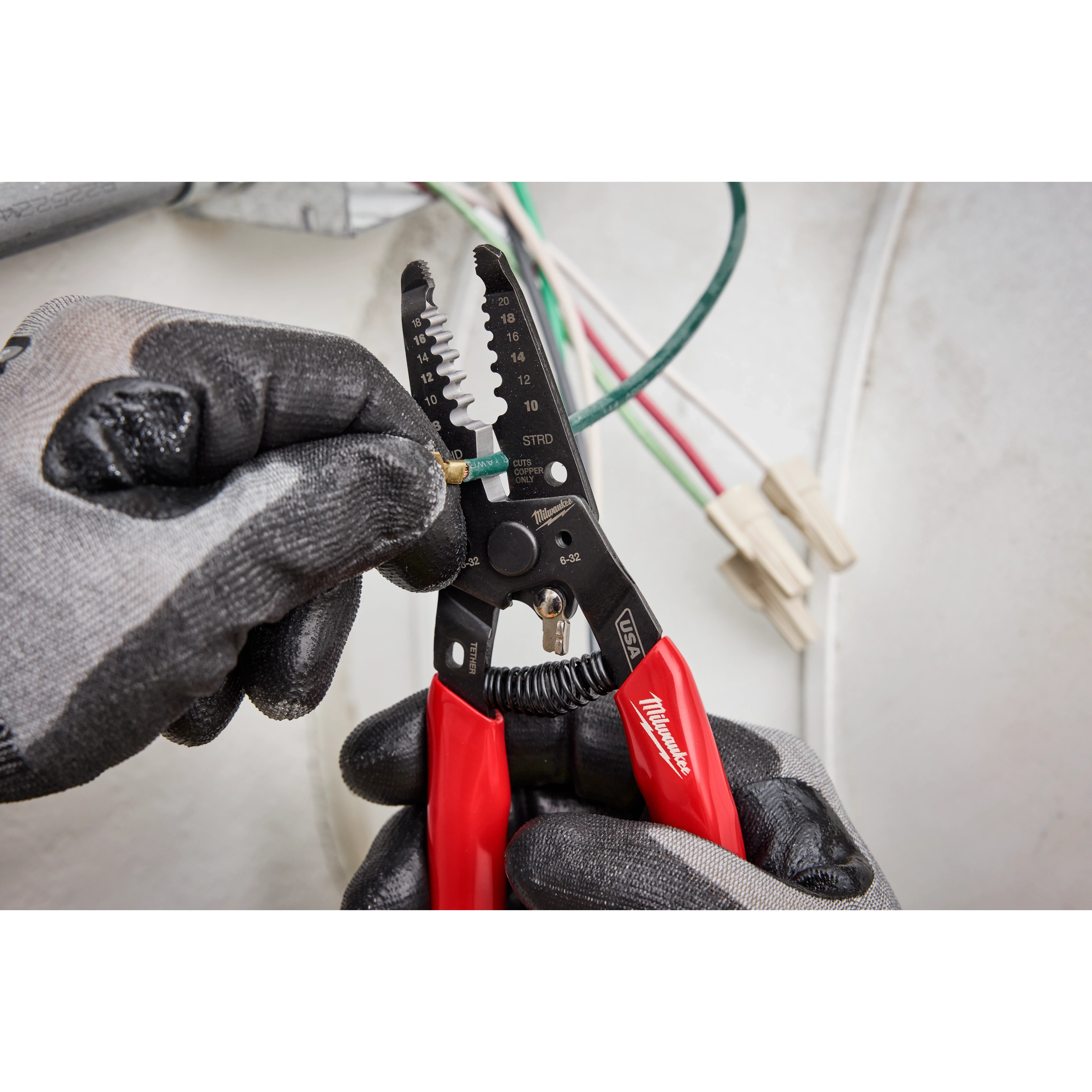 8-20 AWG Dipped Grip Wire Stripper & Cutter (USA) being used by hand in gloves, stripping a green wire.