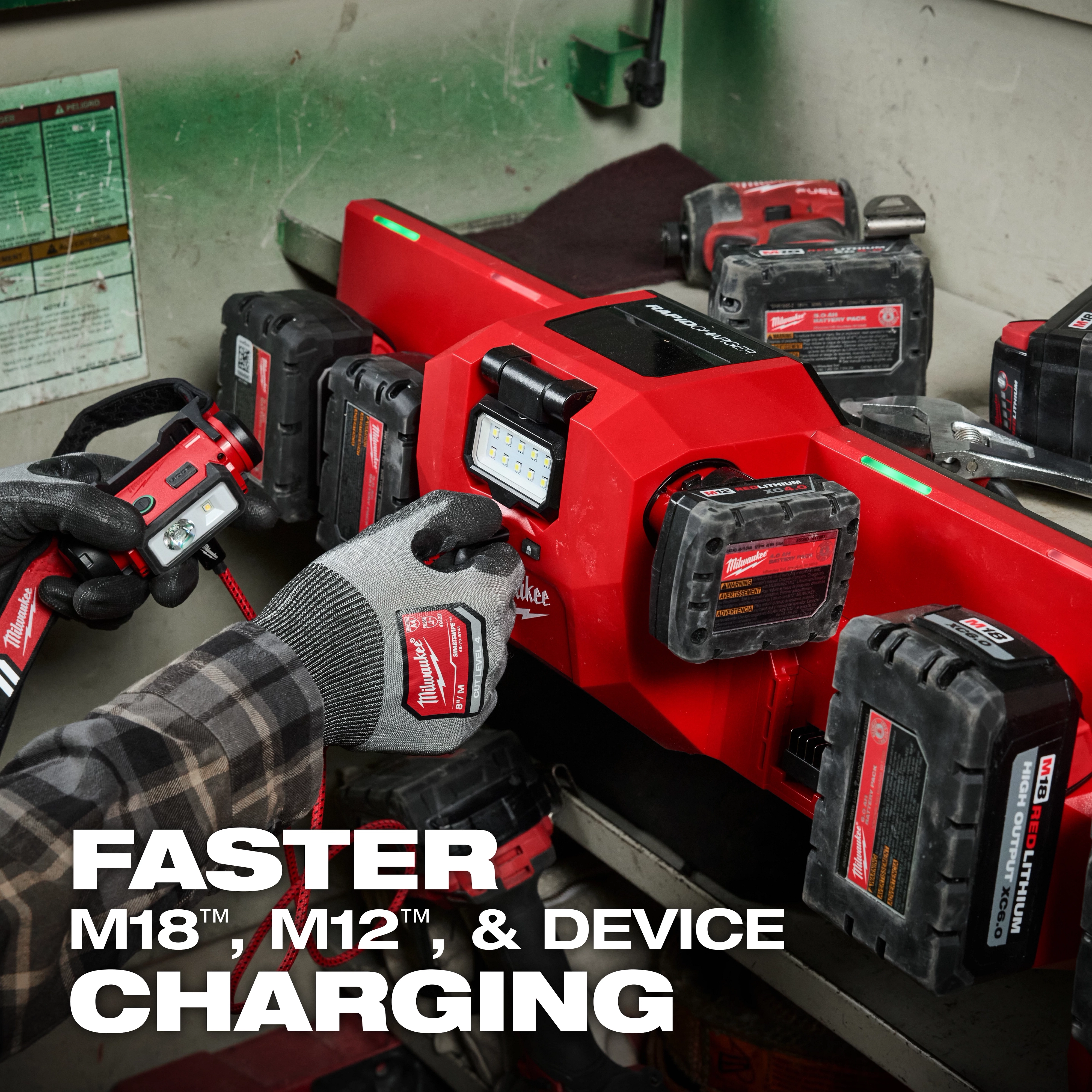 The M18™ and M12™ Gangbox Rapid Charger is displayed charging multiple battery packs in a workshop setting. A person wearing gloves is holding a Milwaukee battery pack near the charger. Text on the image highlights faster charging for M18™, M12™, and devices.