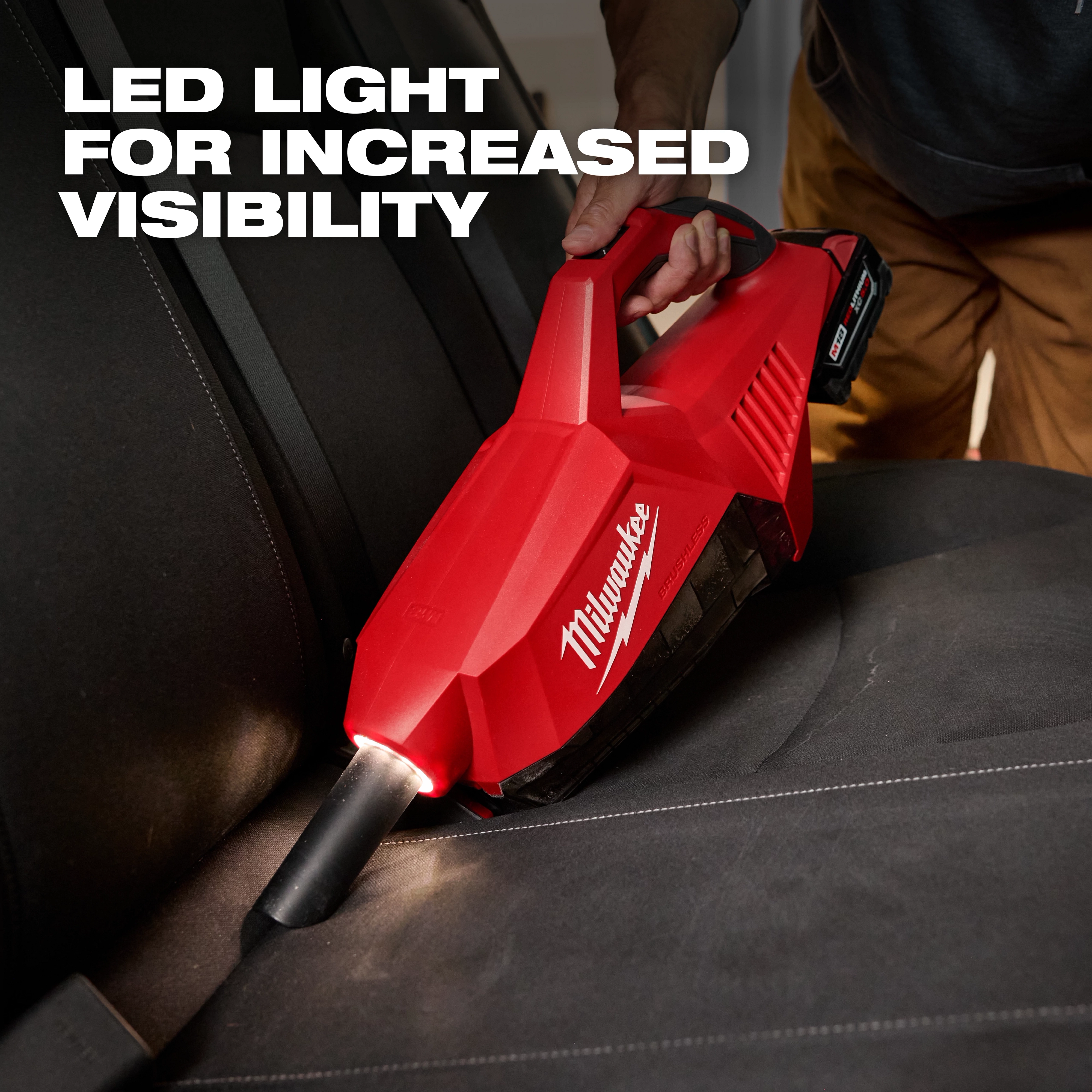 Person using the M18 Brushless Handheld Vacuum with an LED light to clean a car seat, enhancing visibility for thorough cleaning.
