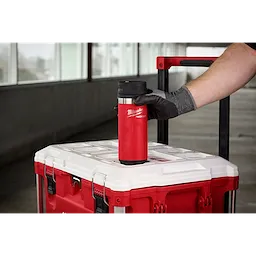 Person places a red PACKOUT 18oz Insulated Bottle with Sip Lid on top of a matching red and white carrying case with a handle.