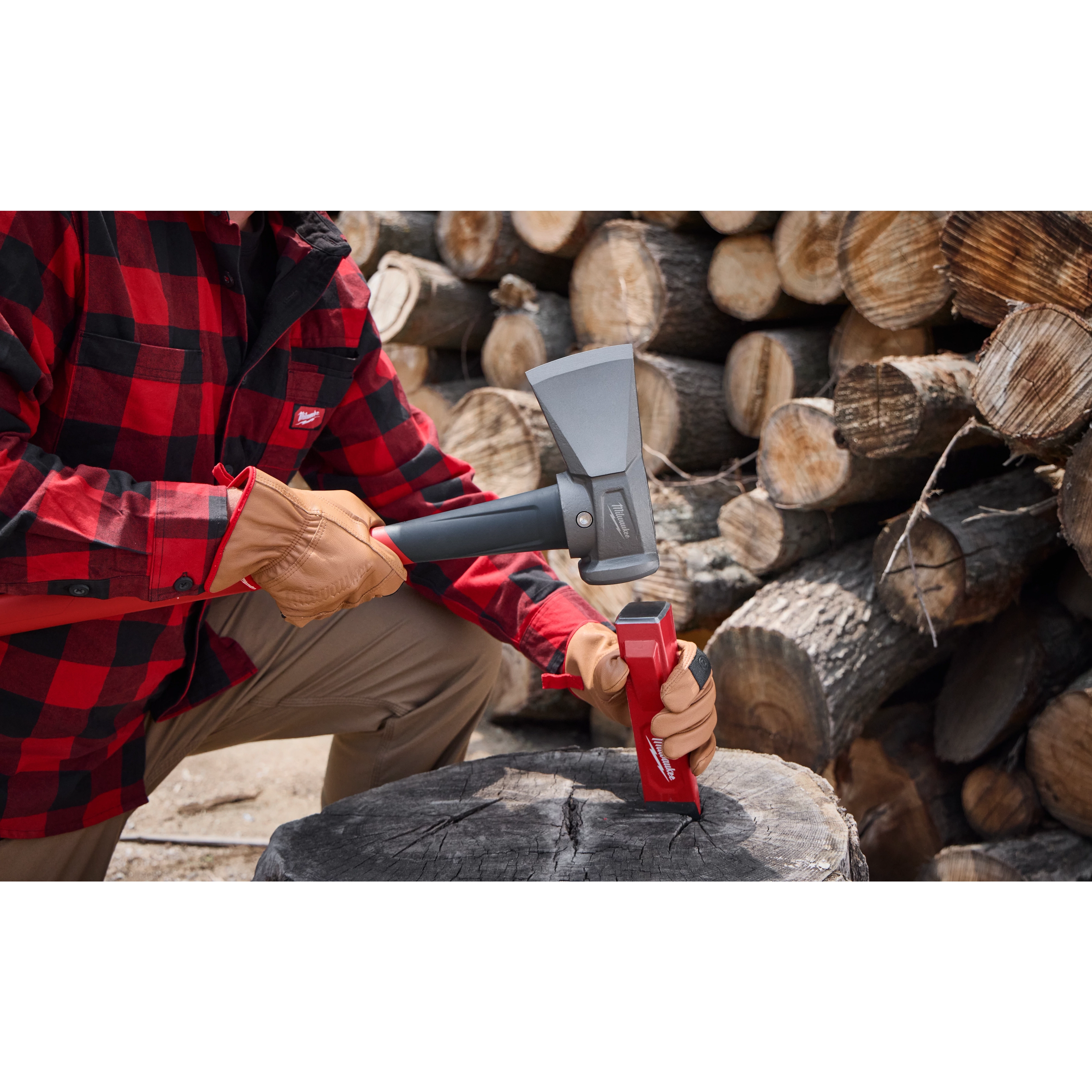 A person in a red checkered shirt and brown gloves uses the 8lb Splitting Maul (36" Handle) to split a log outdoors. A red wood splitter is placed on the log, and stacked firewood is visible in the background.