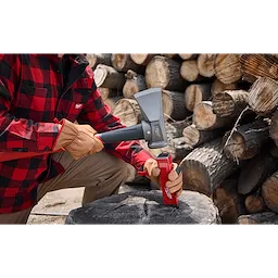 A person in a red checkered shirt and brown gloves uses the 8lb Splitting Maul (36" Handle) to split a log outdoors. A red wood splitter is placed on the log, and stacked firewood is visible in the background.