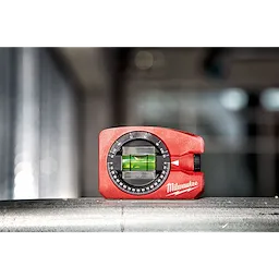 Milwaukee Pocket Level is a compact red leveling tool with a clear vial and adjustable dial, placed on a metallic surface.
