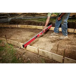 A person uses the Milwaukee REDSTICK Digital Level with PINPOINT Measurement Technology to level the ground at a construction site.
