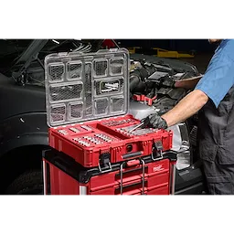 106pc 1/4", 3/8", and 1/2" Drive Bit Socket Set with PACKOUT Organizer open on a red tool stack near a vehicle engine.