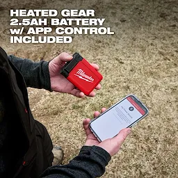 Hands hold a Milwaukee heated gear battery and phone, promoting Milwaukee Heated Merino Wool Crew Neck Baselayer and Baselayer Pants.