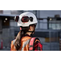A person wearing a BOLT 4PT White Vented Safety Helmet - Type 2, Class C at a construction site.