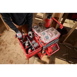 Worker accessing PACKOUT Single Drawer Tool Box stacked with organizers and tools on a construction site floor.