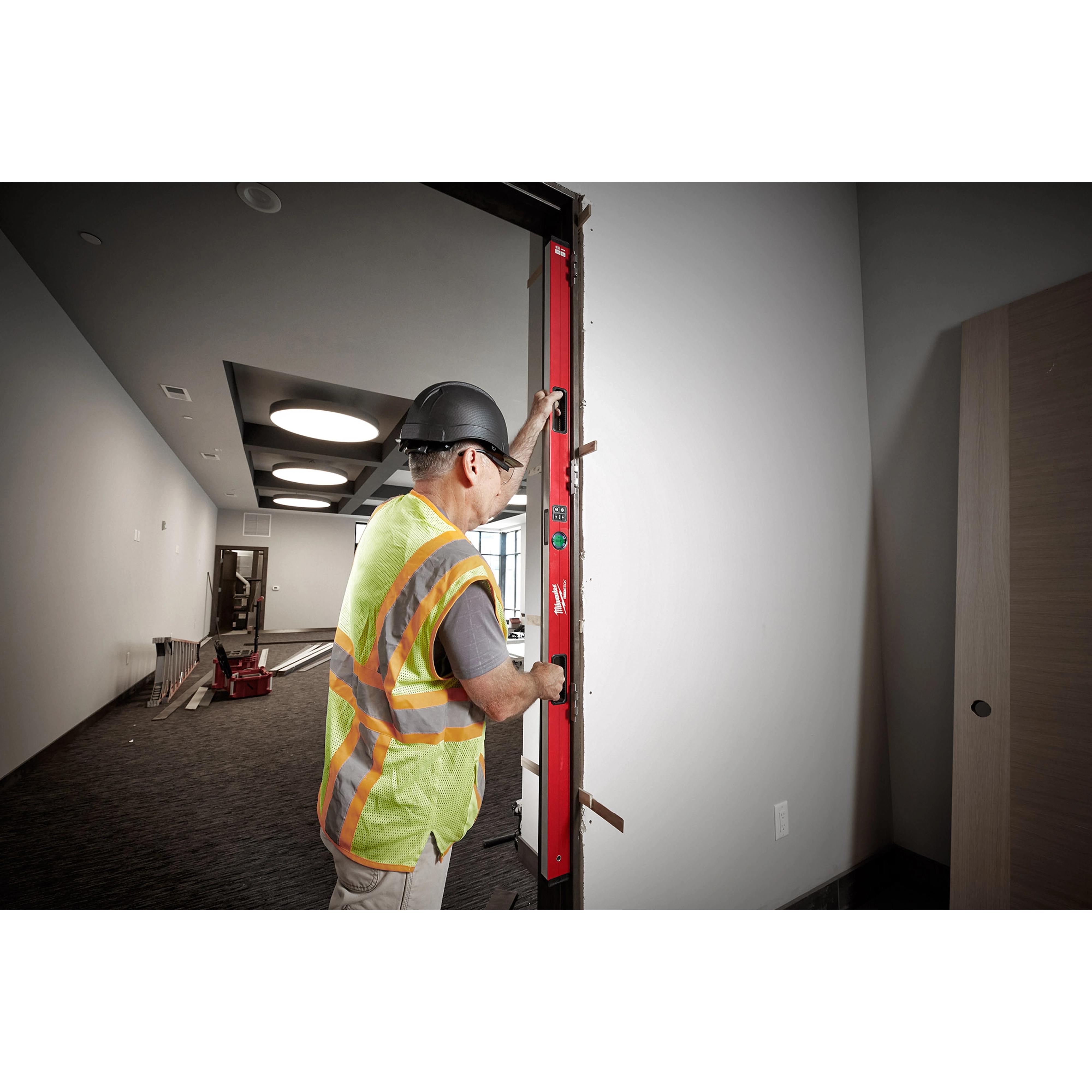 Worker uses Milwaukee REDSTICK Digital Level with PINPOINT Measurement Technology to check the level of a door frame.