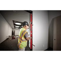 Worker uses Milwaukee REDSTICK Digital Level with PINPOINT Measurement Technology to check the level of a door frame.