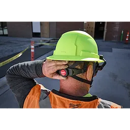 Worker in orange vest adjusts BOLT 4PT High Visibility Green Full Brim Non-Vented Safety Helmet.