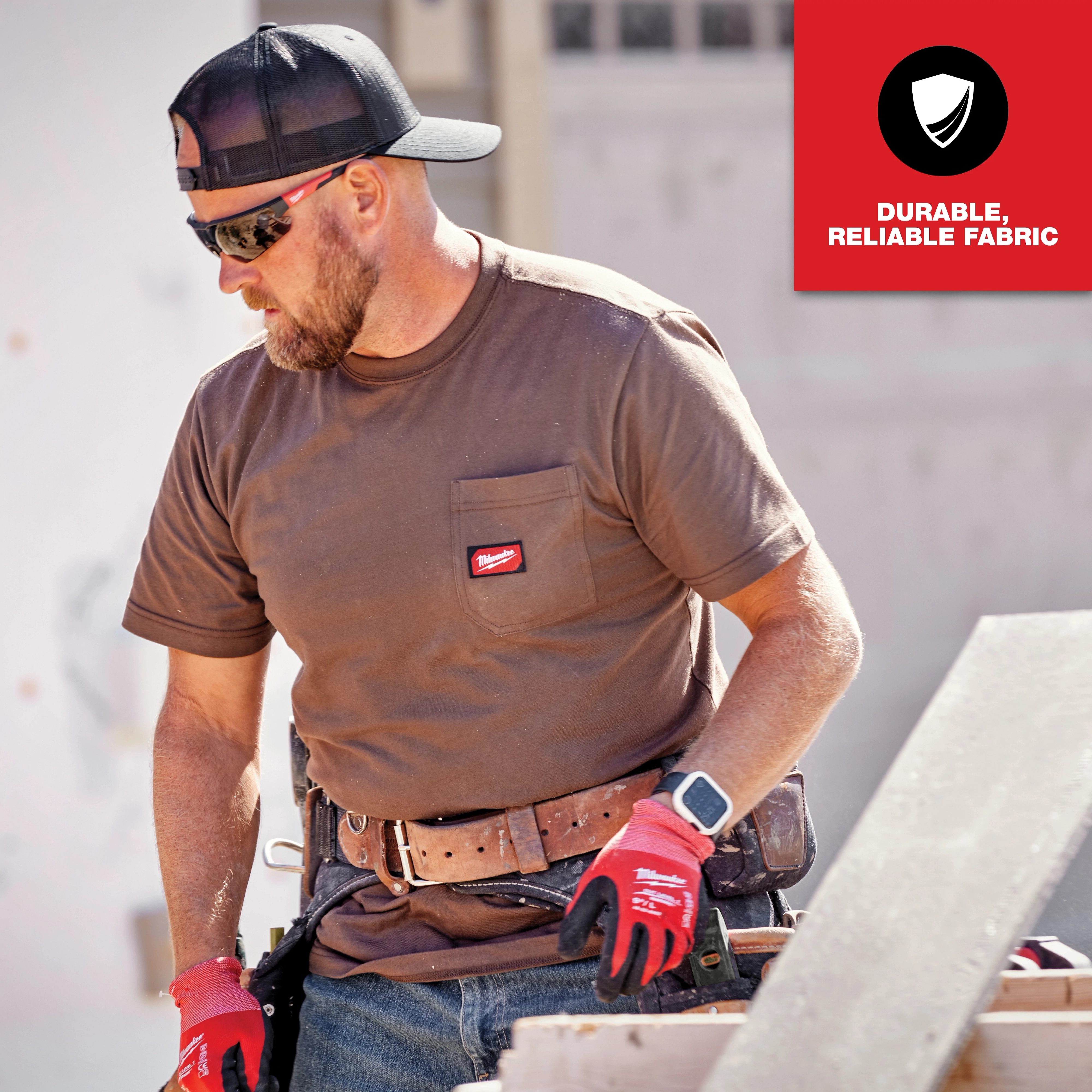 A worker wearing a brown GRIDIRON Pocket T-Shirt - Short Sleeve with visible chest pocket logo, gloves, hat, and tool belt.