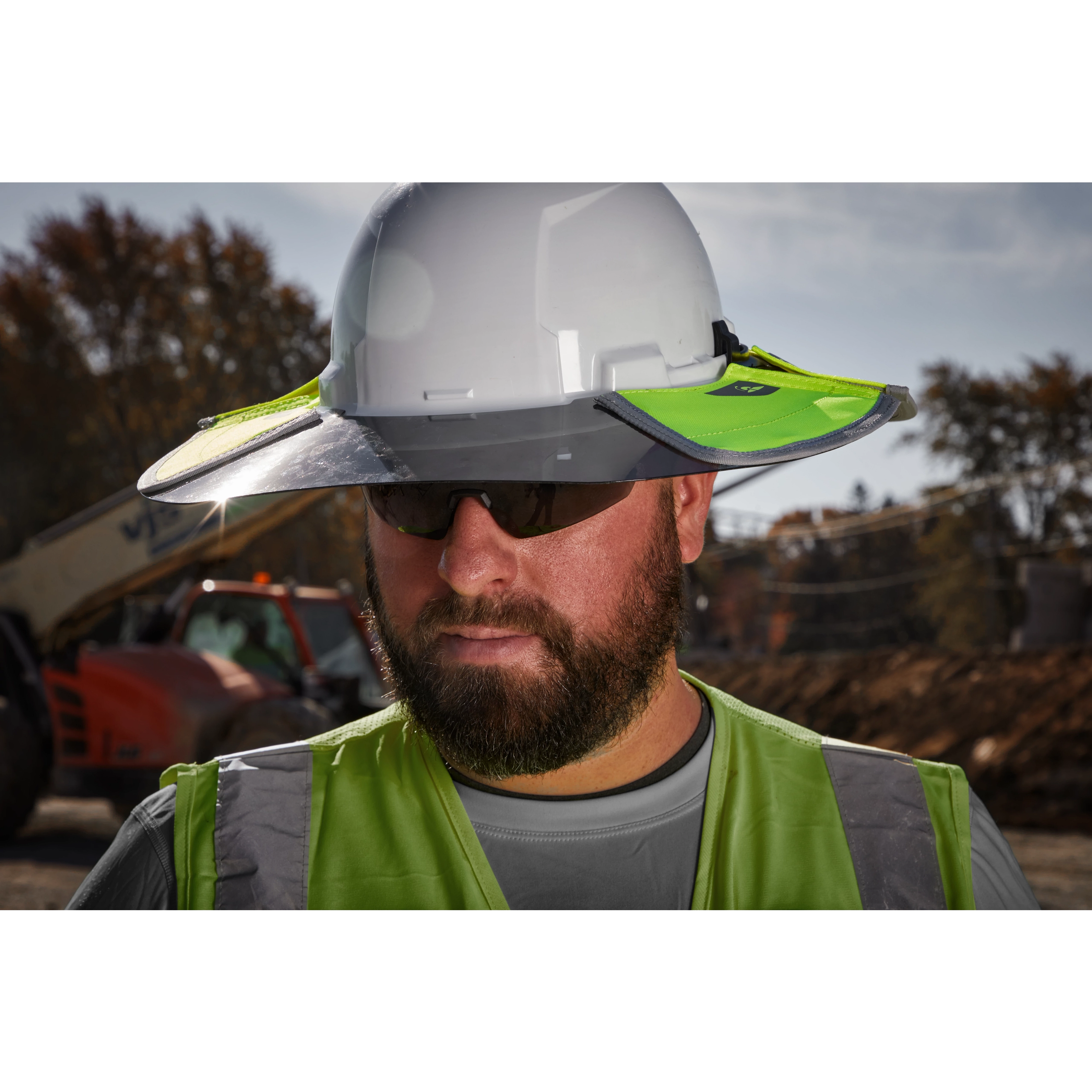 A construction worker wears a white hard hat fitted with a BOLT Sun Visor, featuring bright green accents for increased visibility. The person also wears a grey shirt and a green safety vest.