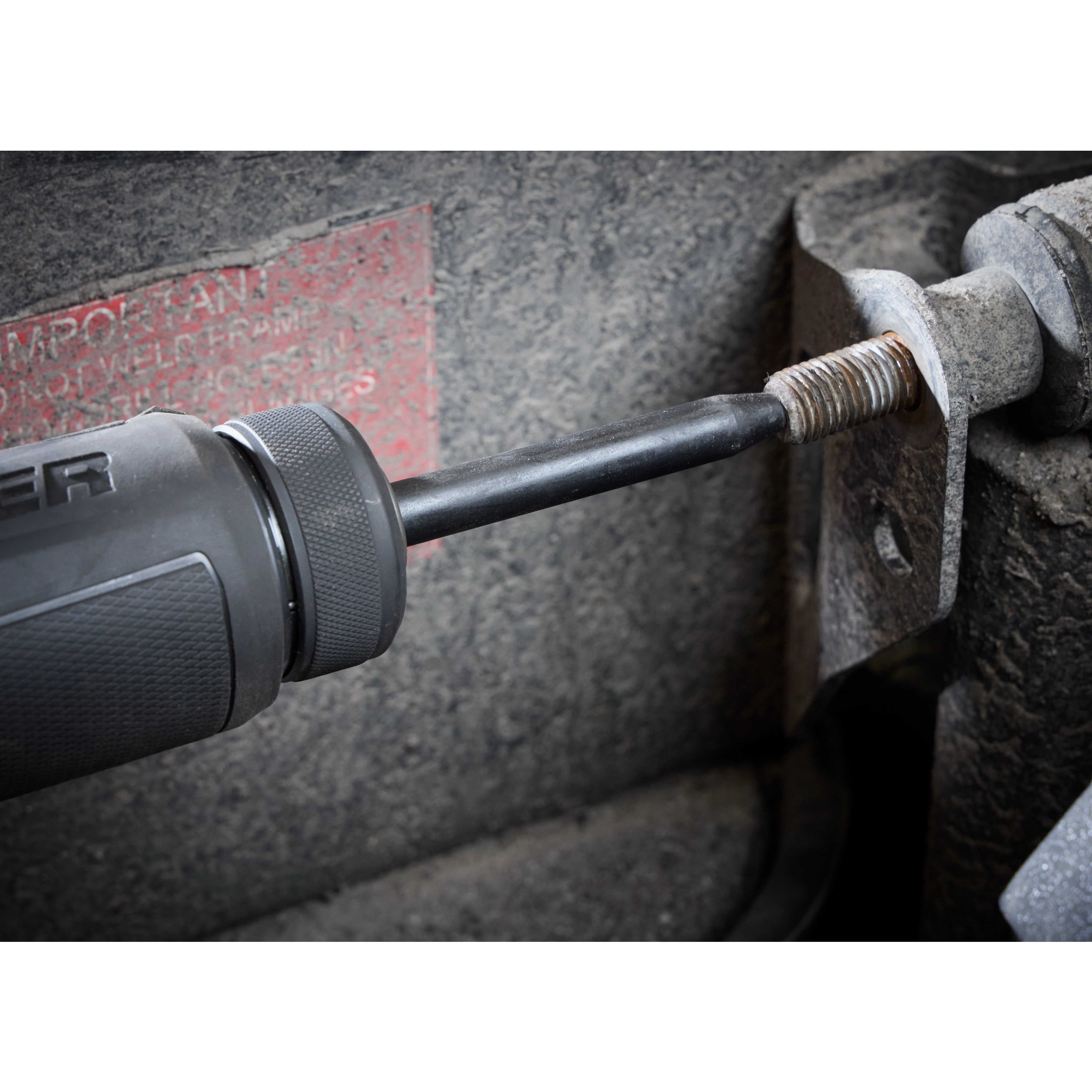 5PC Hammer Chisel Bit Set in use, with the chisel bit attached to a power tool, removing a rusty bolt from a metal surface.