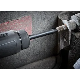 5PC Hammer Chisel Bit Set in use, with the chisel bit attached to a power tool, removing a rusty bolt from a metal surface.