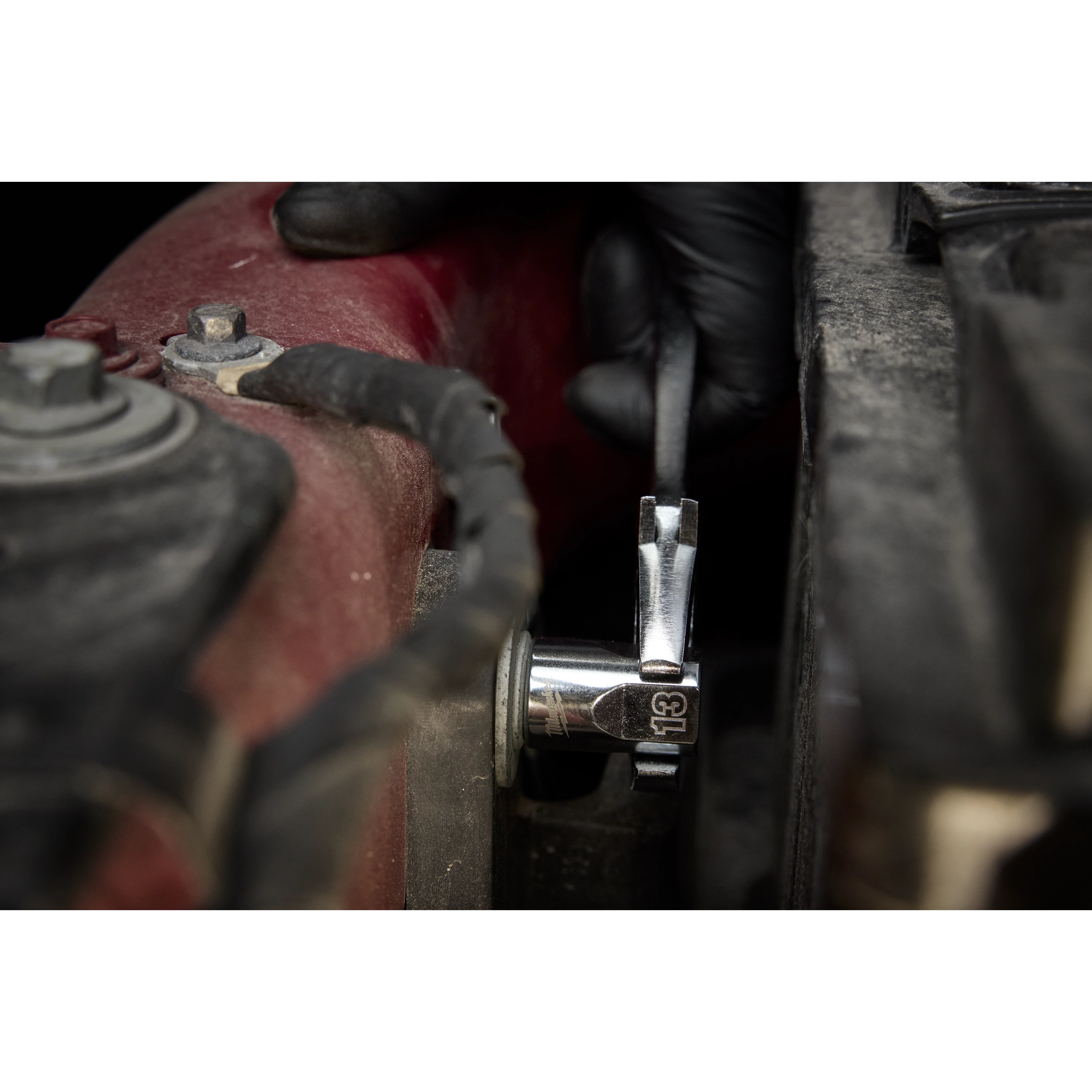 A gloved hand uses a ratchet and socket from the 98pc 3/8" 6-Pt and 12-Pt Metric & SAE Ratchet & Socket Set with PACKOUT™ Low Profile Organizer to tighten a nut on a vehicle part.