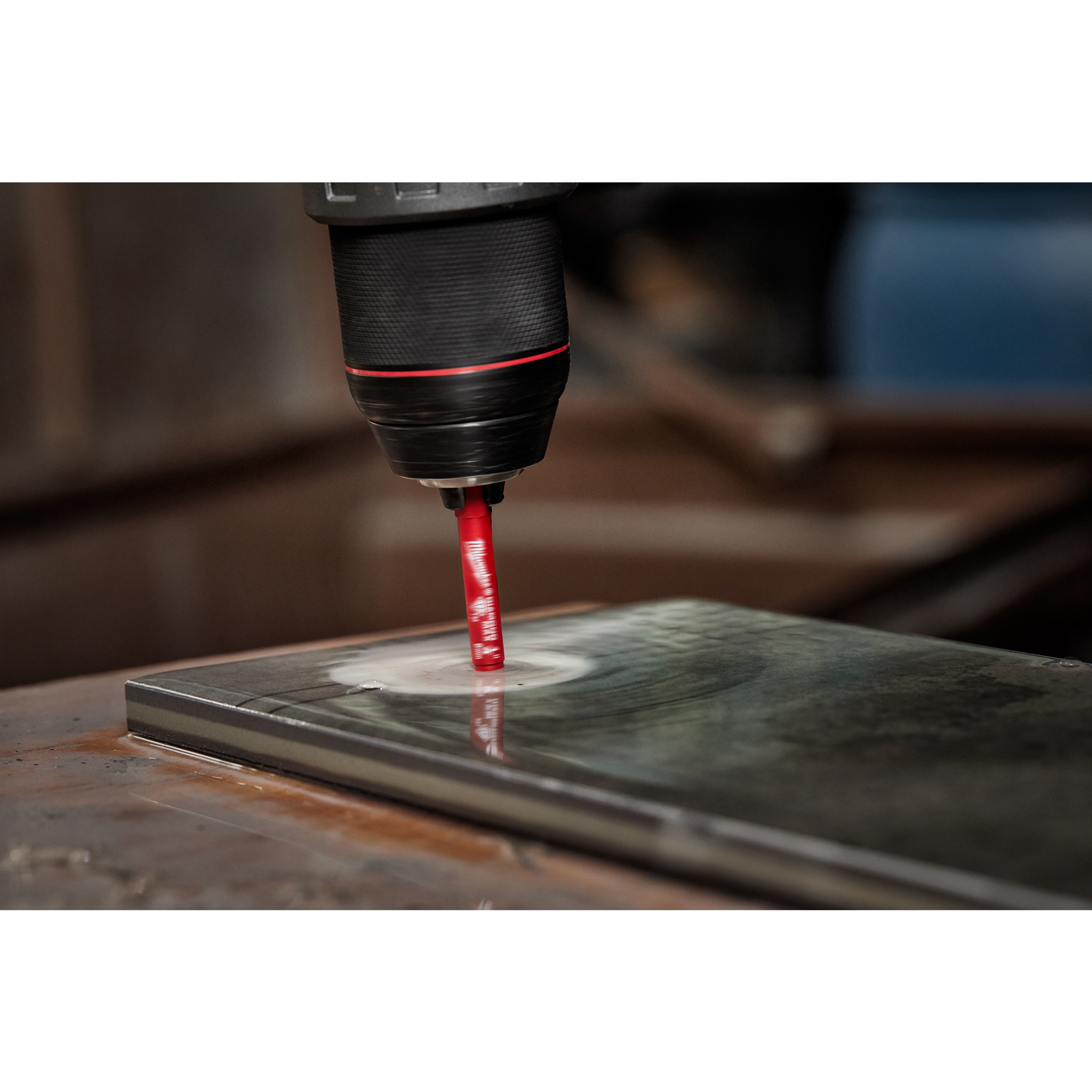 A 1/4" Diamond Grit Hole Saw attached to a drill is cutting a hole into a metallic surface in this close-up image.